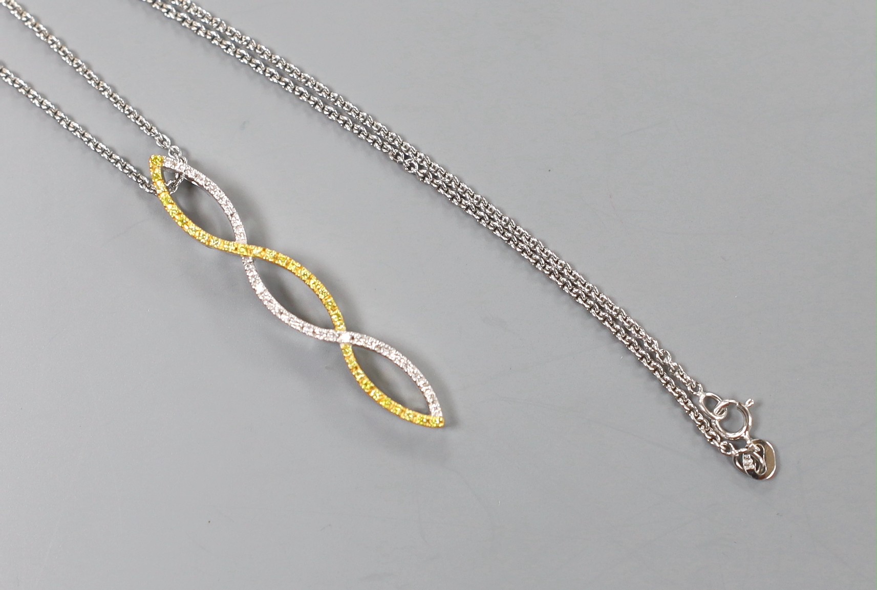 A modern two colour 18ct gold and two colour diamond set overlapping pendant, 42mm, on an 18ct white gold fine link chain, 40cm, 6.9 grams